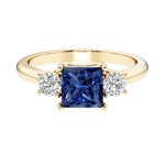 Princess cut 3 stone engagement ring with side diamonds and blue sapphire gemstone center.