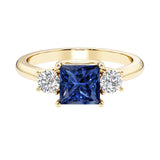 Princess cut 3 stone engagement ring with side diamonds and blue sapphire gemstone center.