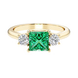 Princess cut 3 stone engagement ring with side diamonds and colombian emerald gemstone center.