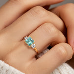 Woman modeling a princess cut three stone engagement ring with paraiba tourmaline and diamonds.