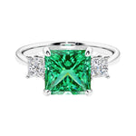 3 stone princess diamond ring in sleek white gold with colombian emerald gemstone center.