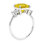 Engagement ring with princess cut diamonds in a 3 stone design featuring yellow sapphire gemstone center.