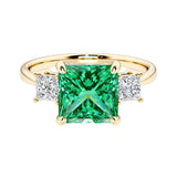 Princess cut 3 stone engagement ring with square side diamonds and colombian emerald gemstone center.