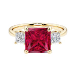 Princess cut 3 stone engagement ring with square side diamonds and ruby gemstone center.