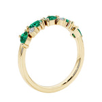 Unique 9 stone half eternity ring with pear shaped green emerald and round diamond accents in yellow gold.