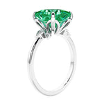 Women's unique ring with lab created green emerald and sparkling round diamonds in a vintage-inspired cluster side stone style.
