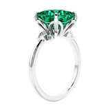 Women's unique ring with lab created green emerald and sparkling round diamonds in a vintage-inspired cluster side stone style.