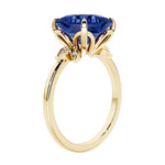 Unique nature inspired ring with princess cut blue sapphire and round diamond accents in yellow gold.