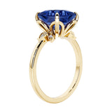 Unique nature inspired ring with princess cut blue sapphire and round diamond accents in yellow gold.