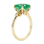 Unique nature inspired ring with princess cut green emerald and round diamond accents in yellow gold.