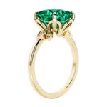 Unique nature inspired ring with princess cut green emerald and round diamond accents in yellow gold.