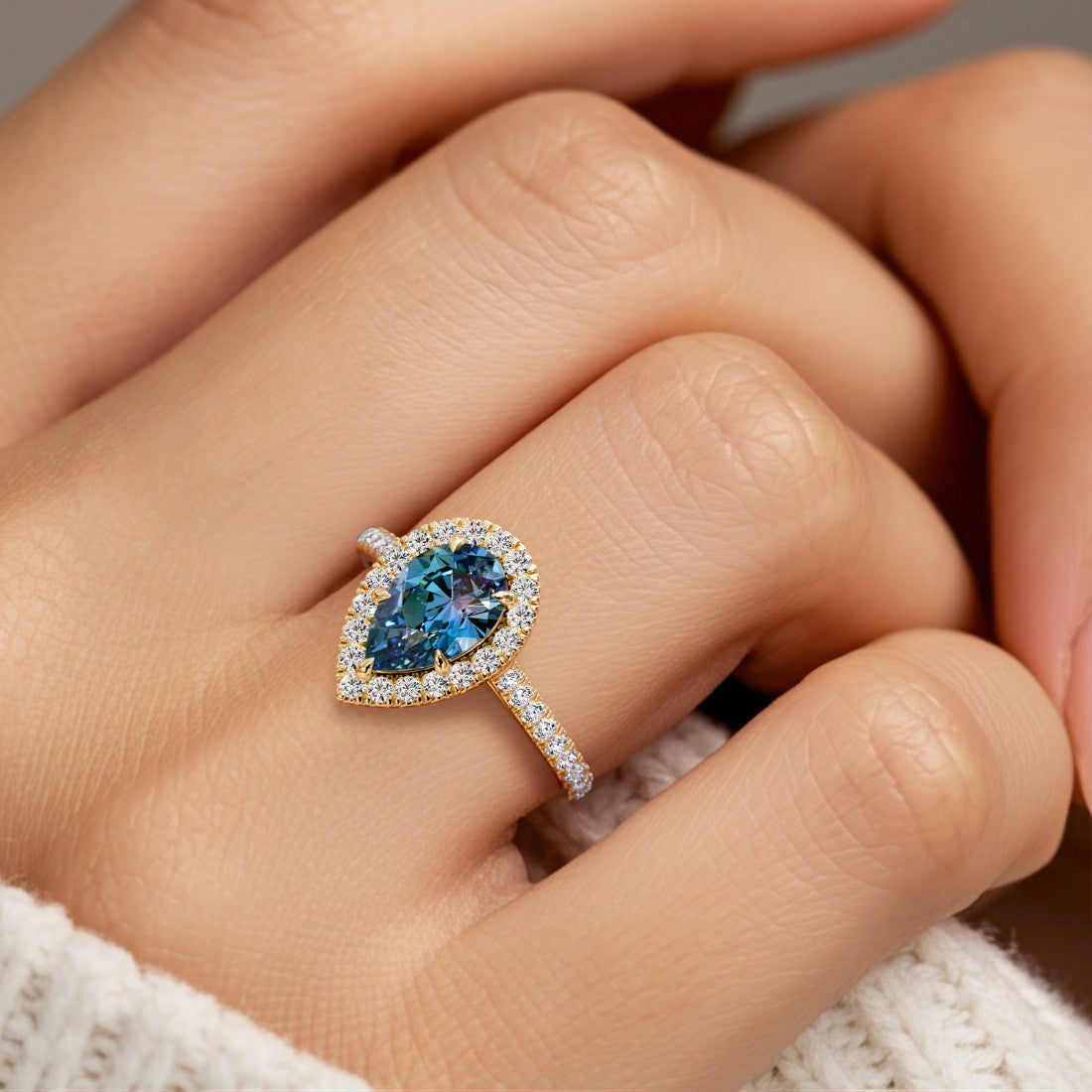 Woman wearing pear shaped alexadrite halo ring with diamonds.