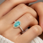 Woman wearing pear shaped alexadrite halo ring with diamonds.