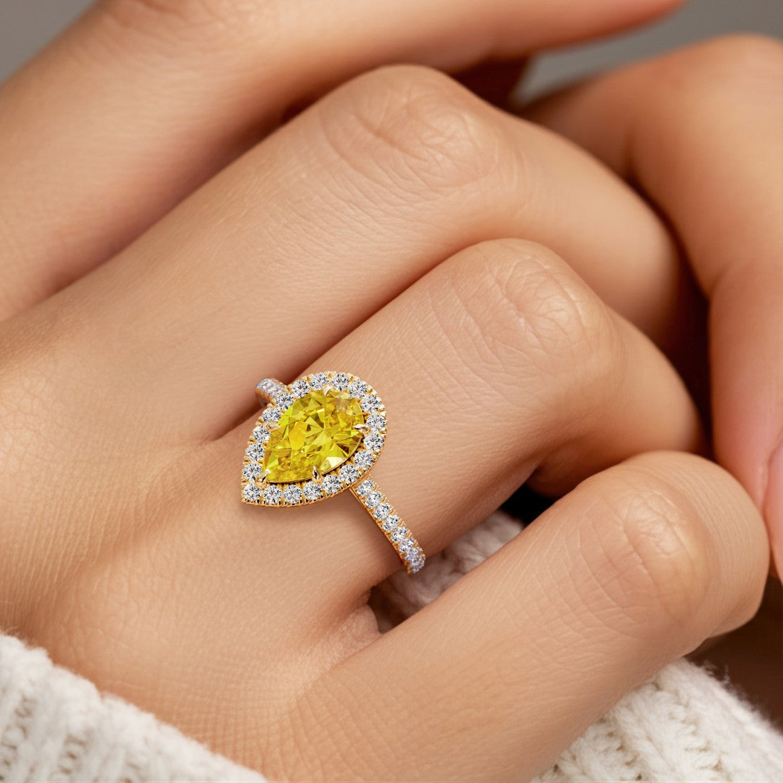 Woman wearing pear shaped alexadrite halo ring with diamonds.