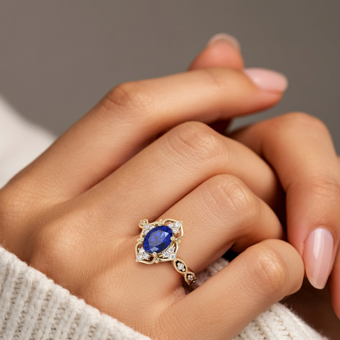 Woman wearing oval cut sapphire and diamond vintage engagement ring.