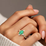 Woman wearing oval cut colombian emerald and diamond vintage engagement ring.
