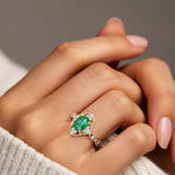 Woman wearing oval cut emerald and diamond vintage engagement ring.