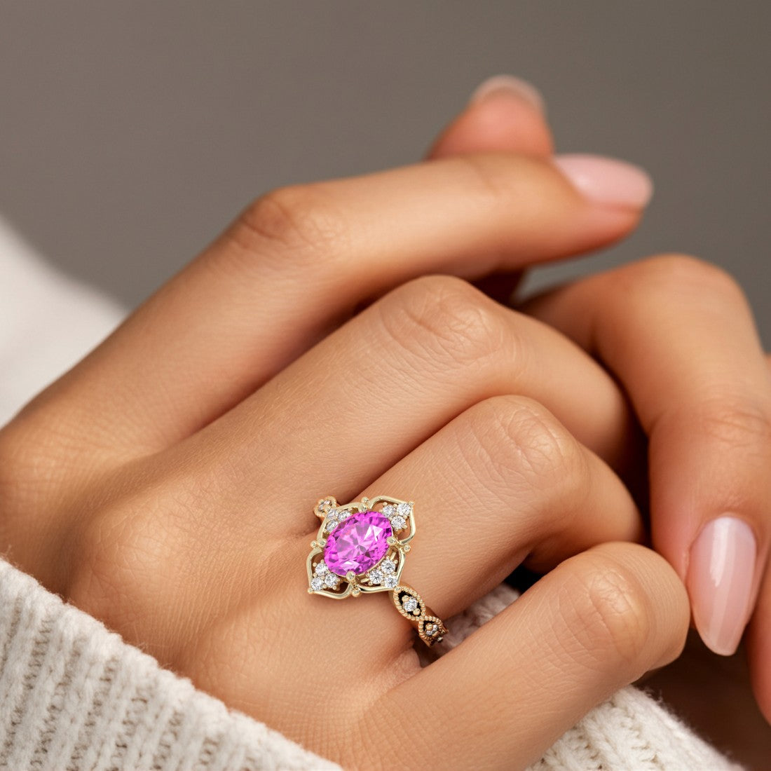 Woman wearing oval cut pink sapphire and diamond vintage engagement ring.
