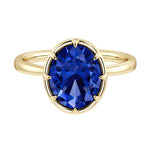 Luxury oval blue sapphire solitaire engagement ring by Pel & Co featuring bezel setting and tapered yellow gold band