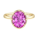 Oval pink sapphire solitaire bezel ring in 14K yellow gold with tapered band by Pel & Co – elegant pink sapphire engagement ring