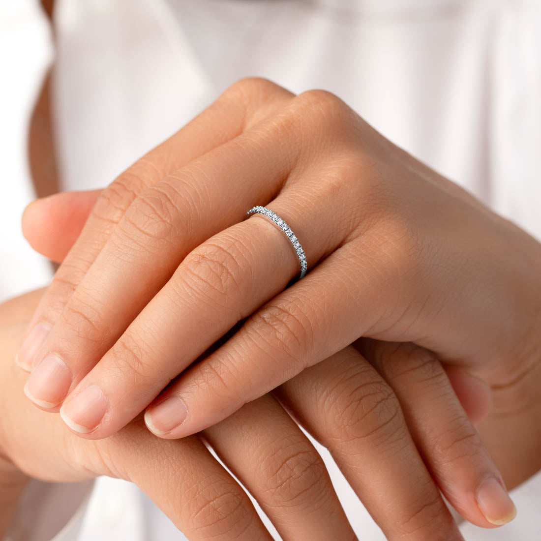 Close-up of hands with a diamond ring on a neutral background