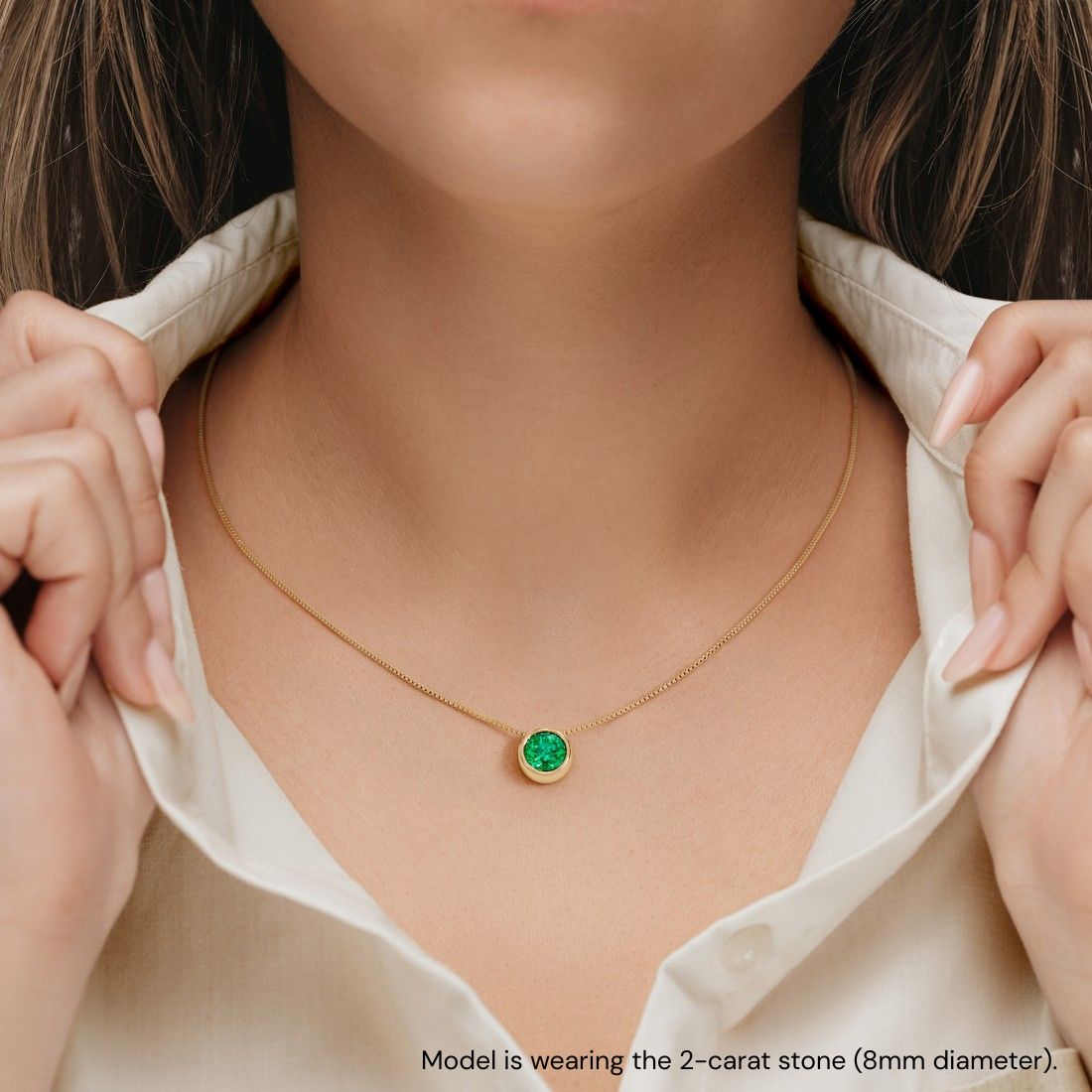 Woman wearing stunning bezel set solitaire pendant necklace with colombian green emerald gemstone by Pel & Co custom emerald jewelry